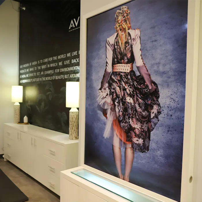 Large framed photograph of a person in a floral dress with their back facing the camera, displayed in a modern room with white cabinets and soft lighting. - Garbo A Salon & Spa TX